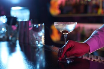 Bartender with fresh Martini cocktail at bar counter, closeup. Space for text