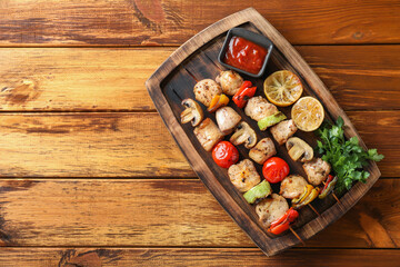 Delicious shish kebabs with grilled vegetables served on wooden table, top view. Space for text
