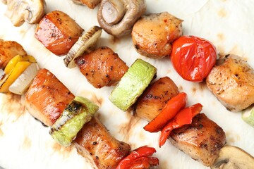 Delicious shish kebabs with mushroom, onion, tomato and zucchini on lavash, top view