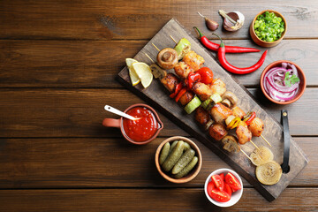 Delicious shish kebabs, mushroom, tomato and zucchini served on wooden table, flat lay. Space for...