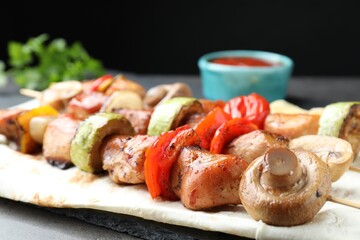 Delicious shish kebabs with mushroom, onion, tomato and zucchini on grey table, closeup