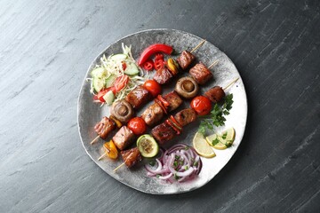 Delicious shish kebabs with vegetables on grey textured table, top view