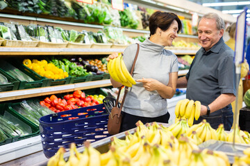 Husband and wife choose banana in fruit department