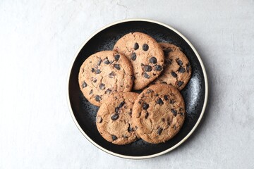 Plate with delicious chocolate chip cookies on light gray table, top view