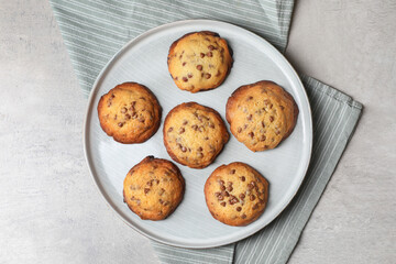 Plate with delicious chocolate chip cookies on gray table, top view
