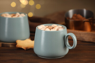Cups of aromatic hot chocolate with marshmallows and cocoa powder on wooden table, closeup