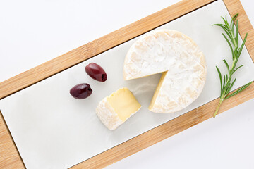 French soft Camembert cheese original Camembert close up Camembert cheese laid out on beautiful stone board decorated with fresh sprig of rosemary, walnuts, and olive. Healthy food. Vitamins protein