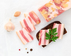 Fototapeta na wymiar Salted lard bacon pork meat slices of almond nuts with black bread sandwich decorated with sprig of fresh parsley on white background close-up. Healthy fats. Healthy food. Vitamins protein. Top view