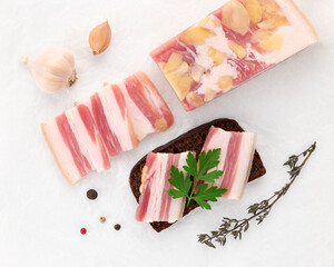 Salted lard bacon pork meat slices of almond nuts with black bread sandwich decorated with sprig of fresh parsley on white background close-up. Healthy fats. Healthy food. Vitamins protein. Top view