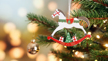 Christmas tree decoration wooden toy horse rotate on branch tree on background bokeh of side flickering light bulbs garlands for family holiday Christmas concept  Happy New Year. Festival mood