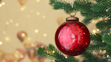 Christmas tree red glass ball on branch close-up decorated burning candles bokeh flickering light bulbs garlands on background. Christmas concept. Celebrate Happy New Year. Noel. Winter holiday family