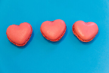 Sweet heart shaped macaroons on blue background. Top view. Valentine Day concept