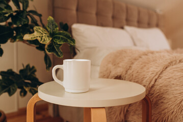 White coffee cup on the table in sunny morning bedroom, mock up.