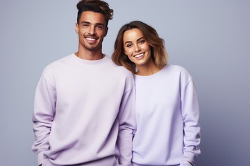 Happy young smiling couple of woman and man wearing lilac sweatshirt on white background.