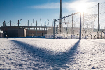Frozen football pitch covered by snow and stadium in the background