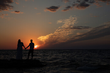 Fototapeta premium Silhouette of man and woman by the sea at sunset