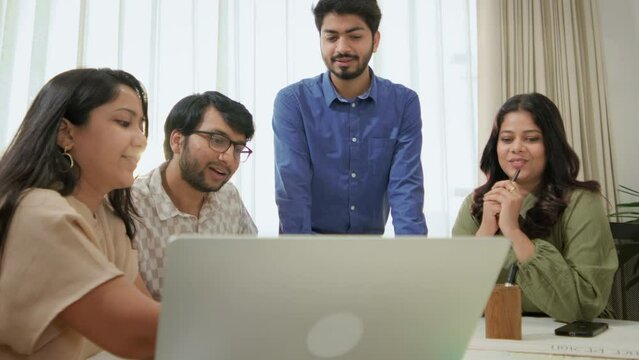 Modern Group of young Indian Corporate Male and Female entrepreneurs Interacting together at a conference table in front of laptop during office meeting. Business people, creative teamwork concept