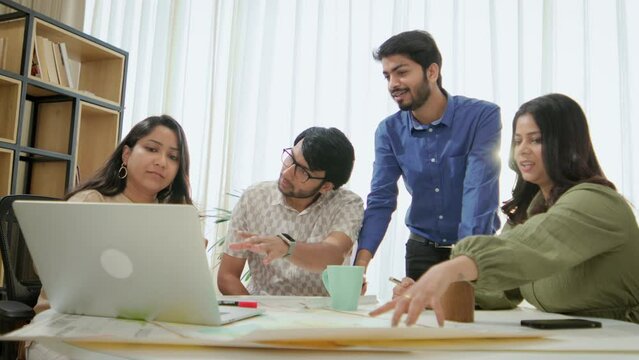 Young Modern Indian Corporate Male and Female entrepreneurs sitting together and discussing at a conference table in front of laptop during office meeting. Business people, creative teamwork concept