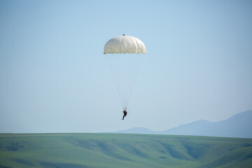 Skydiving. Flying parachutists against the background of the blue sky and mountains. Extreme sport and entertainment.