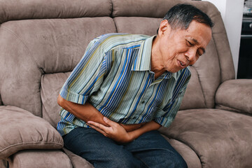 Asian senior man holding stomach having a stomachache