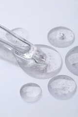 Pipette with samples of cosmetic serum on white background, closeup