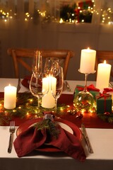 Christmas table setting with burning candles and festive decor