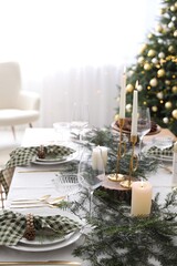 Christmas table setting with festive decor and dishware in room