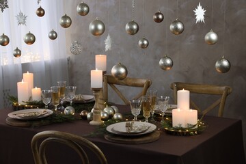 Christmas table setting with burning candles and festive decor