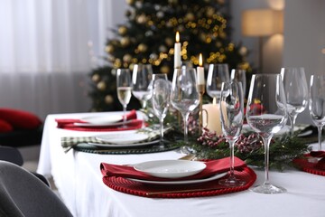 Christmas table setting with festive decor and dishware in room