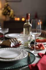 Christmas table setting with bottle of wine, appetizers and dishware indoors