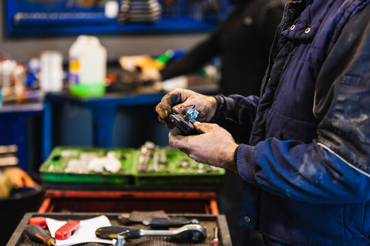 Male mechanic checking a car part for repair in his workshop