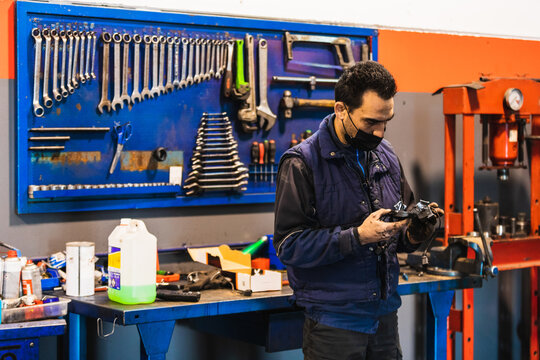 Male mechanic checking a car part for repair in his workshop
