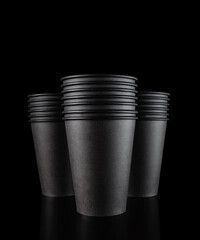 Standing black, brown empty paper glasses stacked on a black background. Selective focus. Isolate. Studio shot.