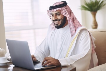Successful muslim businessman in traditional white Kandura uses laptop in his modern office. Successful Saudi, Emirati, Arab businessman - obrazy, fototapety, plakaty