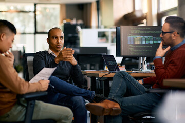 Group of computer programmers talk during meeting while working at IT office.