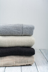 Knitted wool sweaters. Pile of knitted winter clothes on wooden background, sweaters, knitwear, space for text.