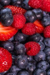 Bright background berry mix of blueberries, raspberries, strawberries, macro photography. Salad of their fresh berries, summer time. Vertical photo