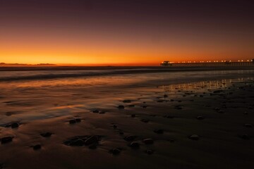 Wooden pier in Oceanside, California at sunset in a gorgeous display of orange and red hues