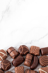 Chocolate praline candies on white background. Top view, copy space. Assortment of various sweet luxury cocoa bonbons.