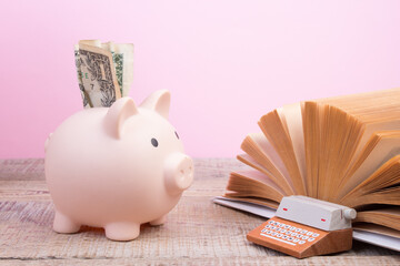 Piggy bank in glasses and books on pink background. open book. Tuition payment. Brainwork....