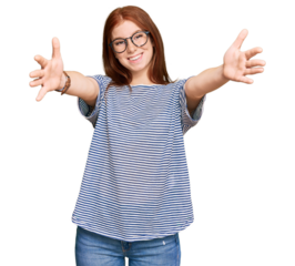 Young read head woman wearing casual clothes and glasses looking at the camera smiling with open arms for hug. cheerful expression embracing happiness.