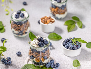 Homemade granola with greek yogurt, maple syrup and fresh blackberries and blueberries in glasses