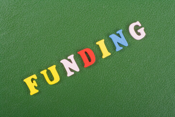 Obraz premium FUNDING word on green background composed from colorful abc alphabet block wooden letters, copy space for ad text. Learning english concept.