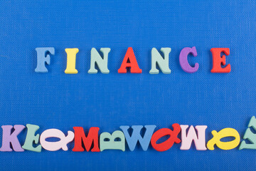 Obraz premium FINANCE word on blue background composed from colorful abc alphabet block wooden letters, copy space for ad text. Learning english concept.