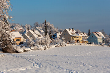 Beautiful winter in a European village - view of a snow-covered field against the backdrop of country houses