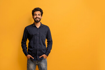 Smiling Young Indian Man Wearing Black Shirt Posing Over Yellow Studio Background
