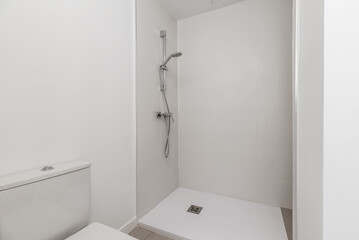 A bathroom with stoneware and white tiles, a shower cabin with a screen and a white resin floor...