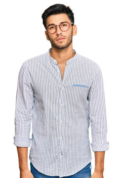 Young handsome man wearing casual clothes and glasses relaxed with serious expression on face. simple and natural looking at the camera.