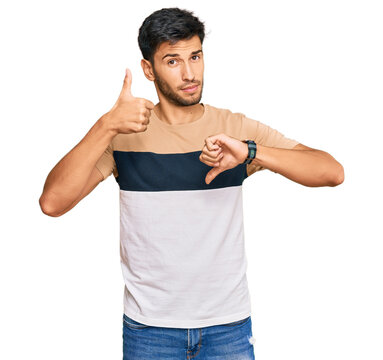 Young handsome man wearing casual clothes doing thumbs up and down, disagreement and agreement expression. crazy conflict