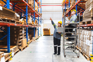 Paper and cardboard factory warehouse workers using a digital tablet while recording inventory. Logistic employees working with business management software in a large storage distribution centre